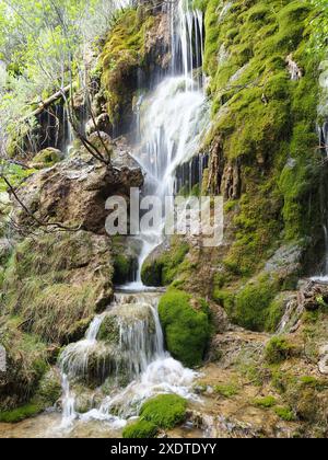 A waterfall cascading among mossy rocks in a forest. Serrania de Cuenca Natural Park, Spain Stock Photo