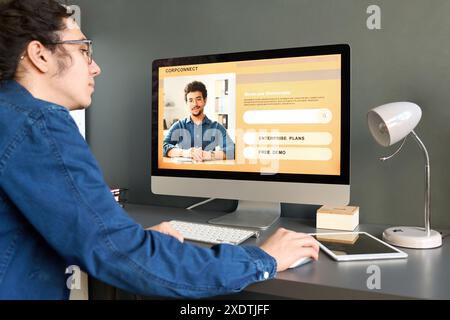 Side view of young man using PC computer with Online business solutions website sitting at workplace in office copy space Stock Photo