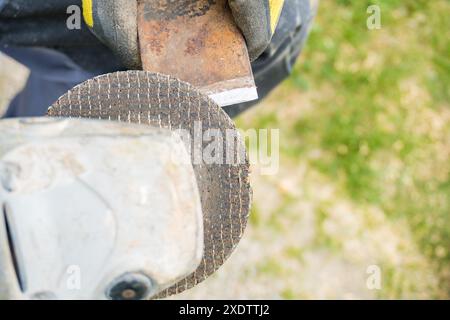 Man holding in hands axe closeup and using sharpening machine. Senior man hands sharpening rusty with whetstone. Male working in carpentry workshop an Stock Photo