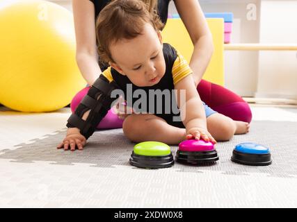 Toddler boy with damage to the central nervous system engages in rehabilitation therapy at children rehab center Stock Photo