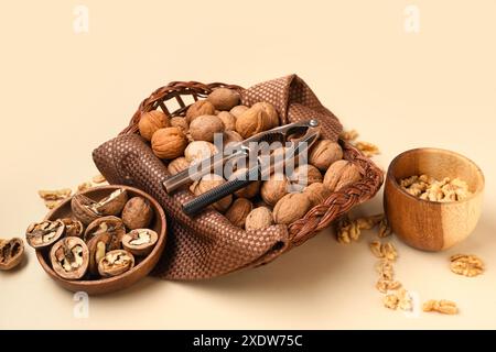 Wicker basket and bowls with walnuts on yellow background Stock Photo