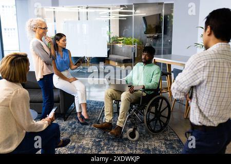 Group of business people in meeting, man in wheelchair using laptop for presentation Stock Photo