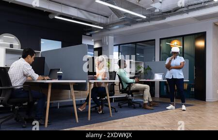 Group of business people working on laptops and discussing in modern office Stock Photo