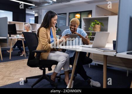 Collaborating in modern office, female showing tablet to male colleague Stock Photo