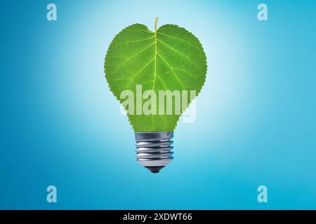 Light bulb with green leaves on blue background. Sustainable energy, Save the Planet, Earth hour concept Stock Photo