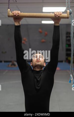 Caucasian man doing pull-ups on trapeze. Warm-up before the climbing wall.  Stock Photo