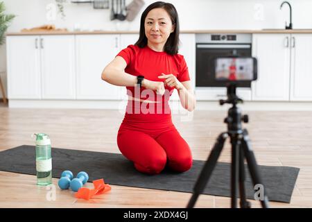 Sporty woman in red talks about smart watch during workout Stock Photo