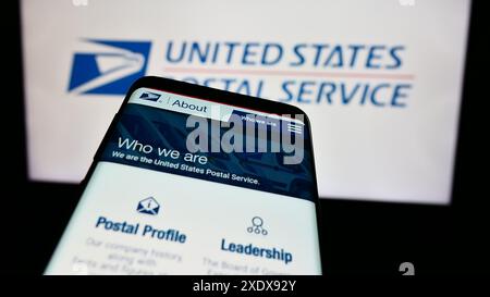 Mobile phone with website of US agency United States Postal Service (USPS) in front of logo. Focus on top-left of phone display. Stock Photo