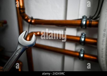 Plumber is holding a wrench and repairing copper water pipes in a boiler room. Stock Photo