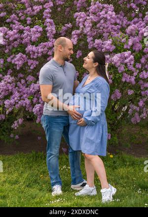 A man tenderly hugs his pregnant wife. The woman is wearing a blue ...