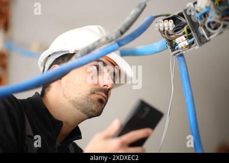 Electrician checking electrical installation using phone in a house under reform Stock Photo