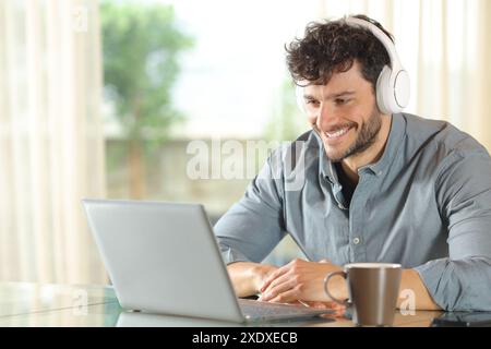 Happy man using laptop on a desk sitting at home Stock Photo
