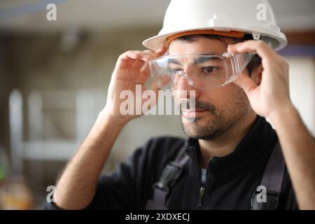 Construction worker putting protective glasses before work in a house under reform Stock Photo