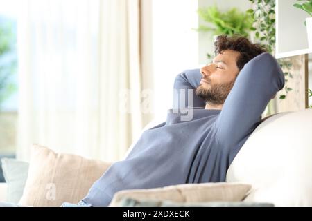 Side view portrait of a serious man resting and relaxing sitting on a sofa at home Stock Photo