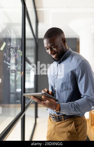Using tablet, male business professional writing on glass wall in office Stock Photo