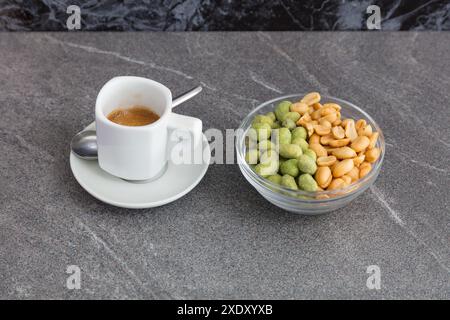 Cup of coffee and roasted mixed nuts on a marble table. Stock Photo