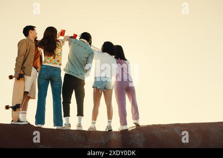 Group of friends drinking and celebrating together outdoors during sunset, enjoying a moment of camaraderie and joy. Stock Photo