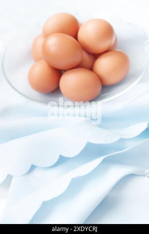 Brown chicken eggs in the glass dish on the festive tablecloth Stock Photo