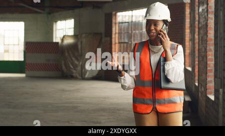 Female Engineer Inspecting Construction Site and Making Phone Call Stock Photo