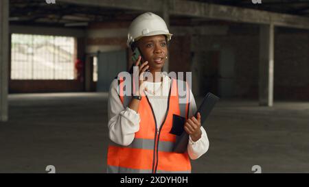 Female Architect Discussing Construction Plans on Phone at Construction Site Stock Photo