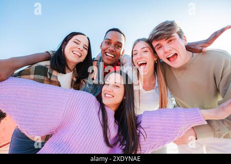 Group of real multiracial teenagers having fun together and posing for a portrait. Young friends smiling and laughing. Multiethnic people bonding outside with positive and friendly expression. High quality photo Stock Photo