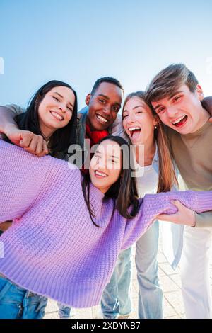 Vertical Group of real multiracial teenagers having fun together and posing for a portrait. Young friends smiling and laughing. Multiethnic people bonding outside with positive and friendly expression. High quality photo Stock Photo