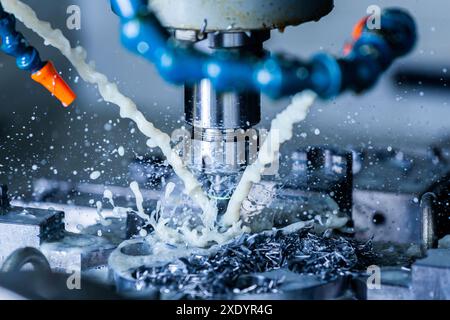 A process of vertical cnc steel milling with external water coolant streams, splashes and a lot of metal chips - close-up with s Stock Photo