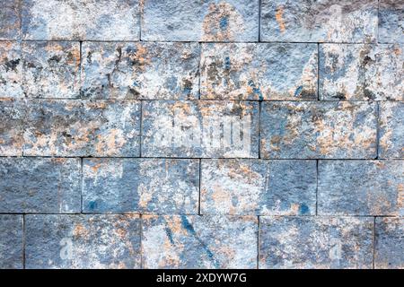 A closeup perspective of a brick wall with various stains covering its surface, showcasing a blend of composite materials and patterns like rectangles Stock Photo