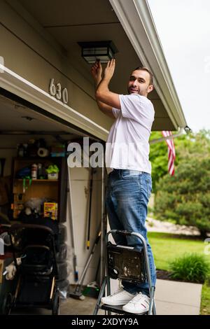 Electrician man hand holding multi meter and checking voltage at the electrical terminal, replacement LED lamp at home outdoor. Maintenance concept. Stock Photo