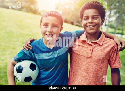 Soccer, hug and portrait of children in park for bonding, games and fun on outdoor holiday together. Sports, kids and happy friends on grass with Stock Photo