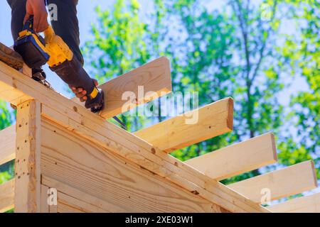 Contractor builder uses cordless reciprocating saw to cut beam during construction Stock Photo