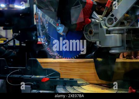 A worker cuts a wooden block using a circular saw Stock Photo