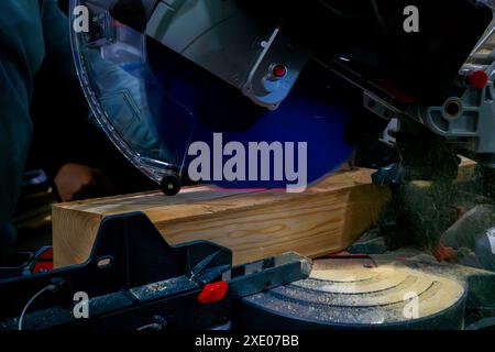 A worker cuts a wooden block using a circular saw Stock Photo