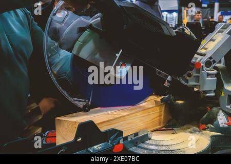 A worker cuts a wooden block using a circular saw Stock Photo