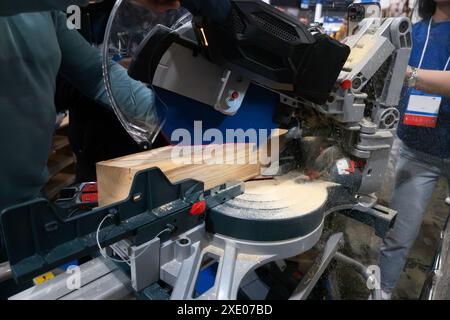 A worker cuts a wooden block using a circular saw Stock Photo