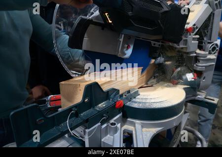 A worker cuts a wooden block using a circular saw Stock Photo
