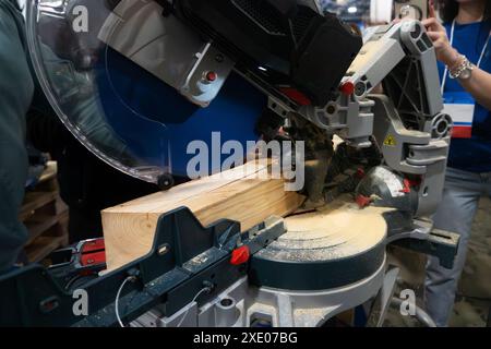 A worker cuts a wooden block using a circular saw Stock Photo