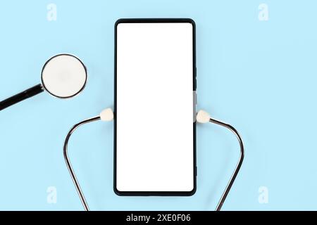 A white cell phone is on a blue background with a stethoscope next to it. Concept of curiosity and wonder Stock Photo