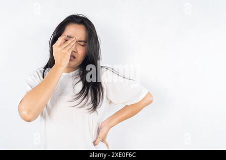 A woman with her eyes closed and her head tilted to the side. She is wearing a white shirt. Beautiful young woman feeling sick, having headache, nose Stock Photo