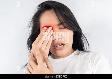 A woman with red eyes and a black face. She is holding her face and rubbing her eyes. Pain. A tired and stressed woman suffers from severe eye pain. Stock Photo