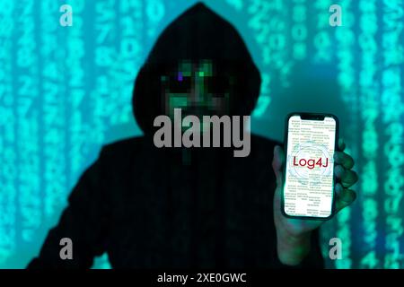 Cybersecurity vulnerability Log4J and hacker,coding,malware concept. Hooded computer hacker in cybersecurity vulnerability Log4J on server room backgr Stock Photo