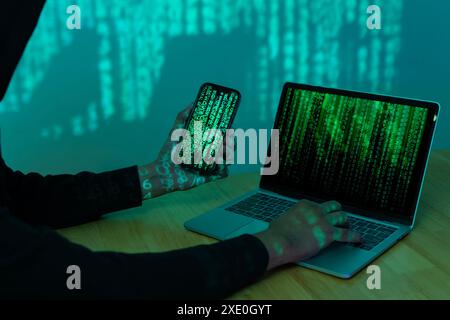 Hacker using computer for organizing massive data breach attack on goverment servers. Hacker in dark room surrounded computers Stock Photo