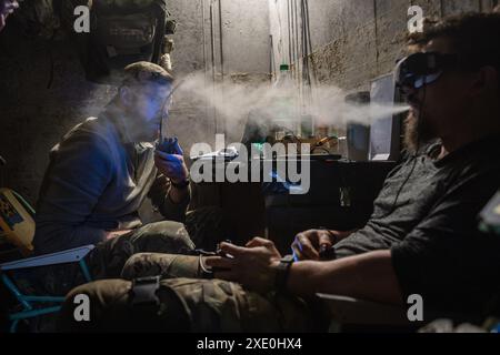 An FPV drone unit from the 92nd Brigade, known as 'Achilles', operates inside a bunker about 10 kilometers from the Russian border in Kharkiv Oblast, Ukraine. First Person View (FPV) drones have changed the nature of warfare in Ukraine, with both Ukrainian and Russian forces coming to rely on these drones, which are armed with explosives and remotely controlled by a pilot wearing a headset. Stock Photo