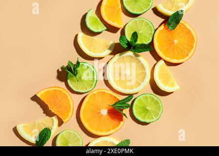 Colorful pattern of citrus fruit slices and mint leaves on pastel orange background, top view. Creative layout of orange, lemon, lime and mint leaves, Stock Photo