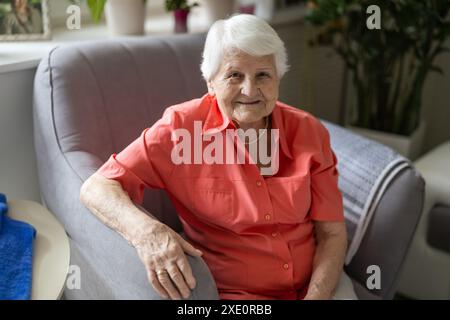 Portrait of happy senior woman sitting in armchair and looking at camera Stock Photo