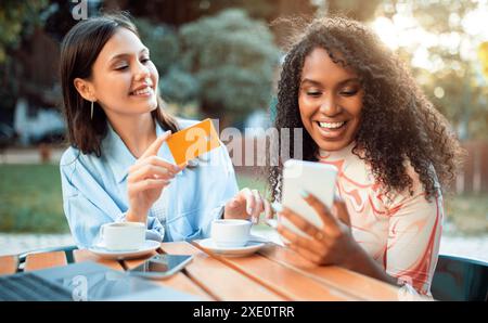 Two Friends Enjoying Coffee and Technology at an Outdoor Cafe Stock Photo