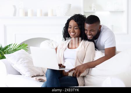Couple Using Laptop on White Couch Stock Photo