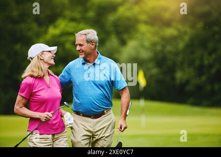 Senior, couple and walking on golf course, outside and healthy fitness activity with golfers together with club. Relaxing, weekend break and happy Stock Photo