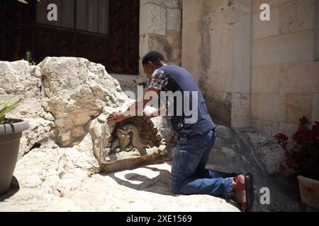 Black Nigerian man, a Muslim, who converted to Pentecostal Christianity kneels on Rock of Agony in the Garden of Gethsemane is praying & meditating Stock Photo