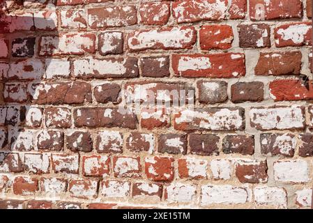 Previously painted brick wall with remnants of white paint on red clay bricks. Stock Photo